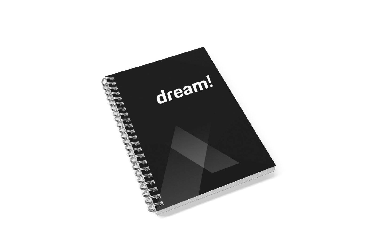 Un carnet noir à spirales avec le mot "dream !" écrit en blanc sur la couverture, posé sur une surface blanche.